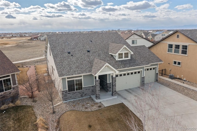 view of front of property with a garage, concrete driveway, stone siding, roof with shingles, and a residential view