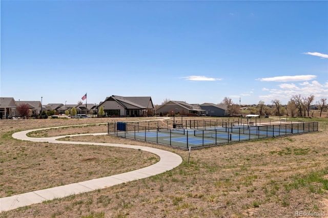 view of pool featuring a tennis court, fence, and a residential view