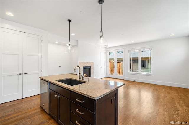 1934 S Sherman St, Denver, CO 80210 - kitchen featuring stainless steel dishwasher, dark brown cabinets, wood finished floors, open floor plan, and pendant lighting
