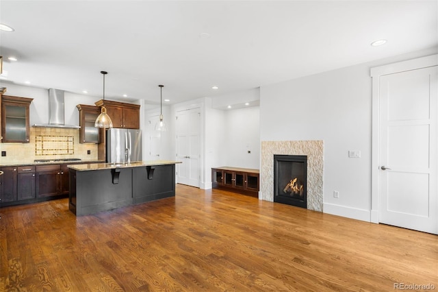1934 S Sherman St, Denver, CO 80210 - kitchen featuring wall chimney exhaust hood, stainless steel appliances, decorative backsplash, a kitchen breakfast bar, and glass insert cabinets