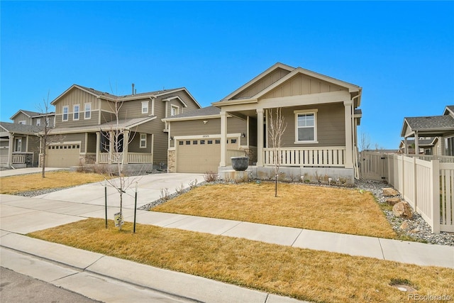 craftsman-style home featuring board and batten siding, fence, a porch, concrete driveway, and an attached garage
