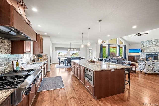 6331 County Road 32, Platteville, CO 80651 - kitchen with appliances with stainless steel finishes, a sink, premium range hood, wood finished floors, and a breakfast bar