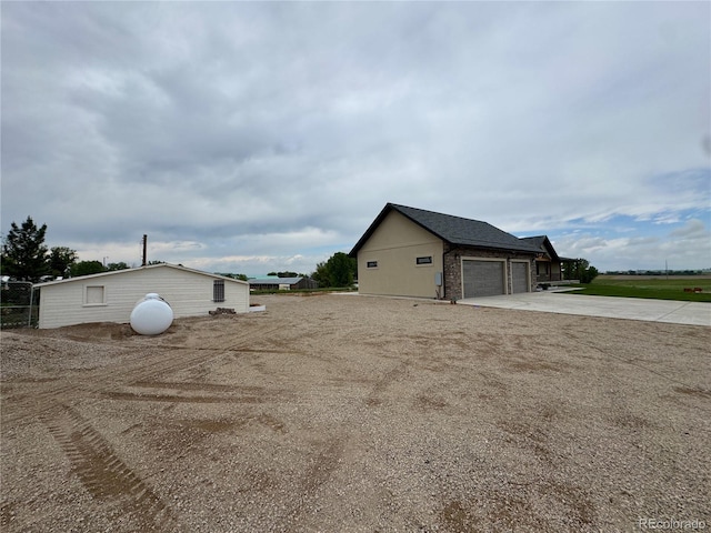 6331 County Road 32, Platteville, CO 80651 - view of side of home with driveway, an attached garage, and an outbuilding