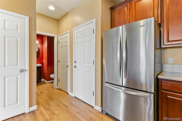 1284 Timber Run Hts, Monument, CO 80132 - kitchen with freestanding refrigerator, light wood finished floors, light countertops, and brown cabinetry