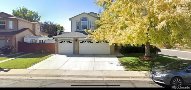 view of front of property featuring an attached garage, concrete driveway, a front lawn, and fence