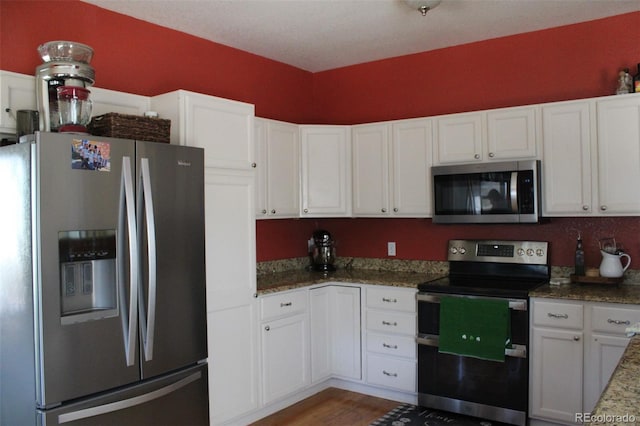 kitchen with stone countertops, stainless steel appliances, wood finished floors, and white cabinetry