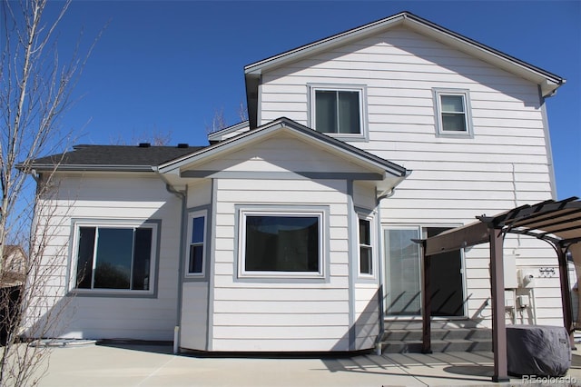 rear view of property featuring a pergola and a patio