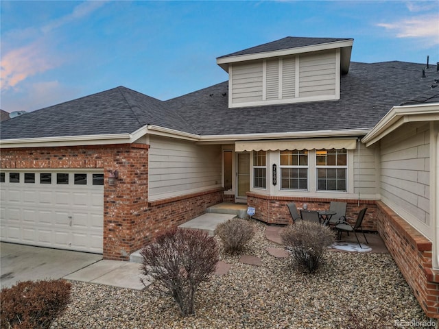 view of front of property featuring brick siding, roof with shingles, and an attached garage