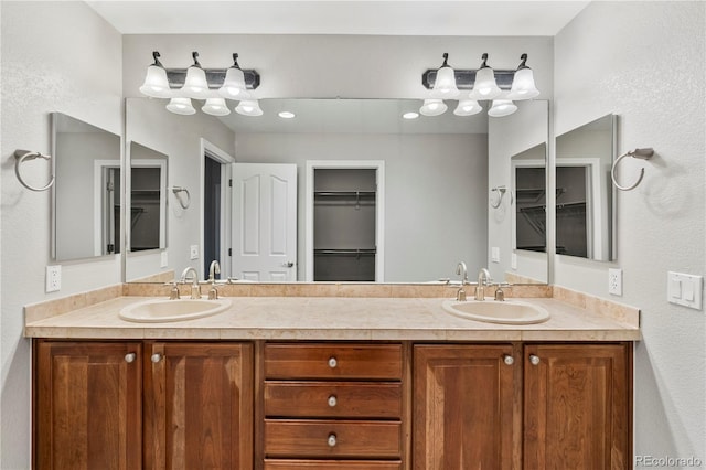 bathroom with double vanity, a spacious closet, and a sink