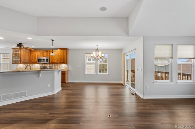 kitchen featuring visible vents, a kitchen bar, backsplash, appliances with stainless steel finishes, and brown cabinetry