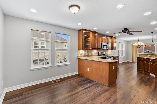 kitchen with visible vents, backsplash, glass insert cabinets, a peninsula, and stainless steel appliances