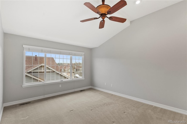 carpeted spare room with a ceiling fan, vaulted ceiling, visible vents, and baseboards