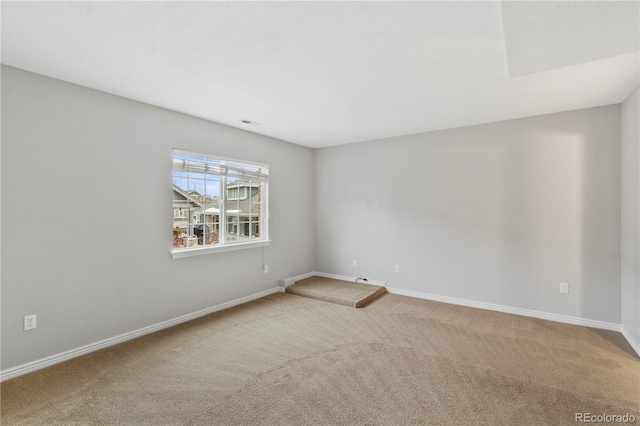 carpeted spare room with visible vents and baseboards