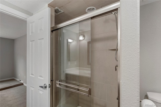 bathroom with visible vents, toilet, a stall shower, baseboards, and a textured wall