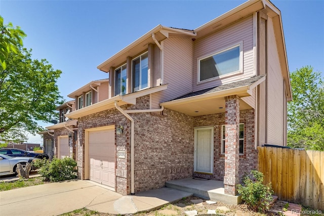 2035 Overland Dr, Brighton, CO 80601 - townhome / multi-family property with fence, a garage, concrete driveway, and brick siding