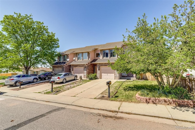 2035 Overland Dr, Brighton, CO 80601 - townhome / multi-family property with concrete driveway, an attached garage, fence, and stone siding