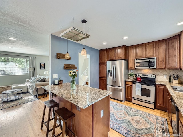 6664 Gray St, Arvada, CO 80003 - kitchen featuring stainless steel appliances, light stone countertops, decorative backsplash, light wood-style flooring, and recessed lighting