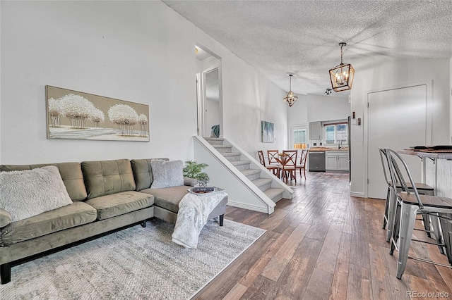 4726 S Taft St, Morrison, CO 80465 - living area featuring vaulted ceiling, a textured ceiling, wood-type flooring, a chandelier, and stairway