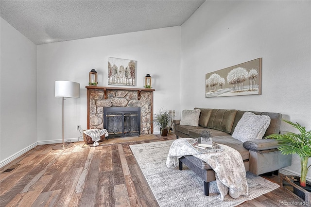 4726 S Taft St, Morrison, CO 80465 - living room with wood finished floors, lofted ceiling, a stone fireplace, and a textured ceiling