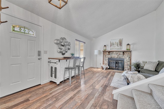 4726 S Taft St, Morrison, CO 80465 - living room featuring hardwood / wood-style floors, a textured ceiling, vaulted ceiling, and a fireplace