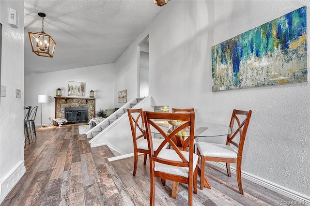 4726 S Taft St, Morrison, CO 80465 - dining area with wood finished floors, a chandelier, stairway, a stone fireplace, and a textured wall