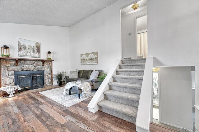 4726 S Taft St, Morrison, CO 80465 - living area featuring wood finished floors, a textured ceiling, a stone fireplace, and stairs