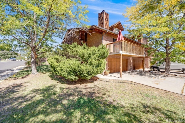 view of home's exterior with a garage, a deck, a chimney, brick siding, and concrete driveway