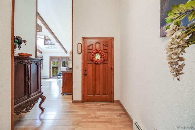 interior space featuring baseboards, baseboard heating, a high ceiling, and light wood-style flooring
