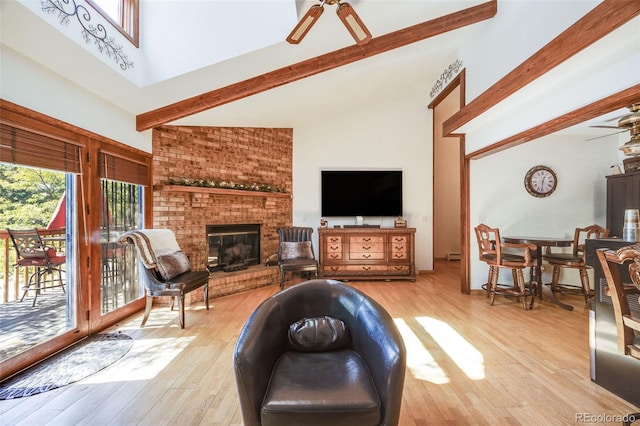 living room featuring a brick fireplace, ceiling fan, wood finished floors, and beamed ceiling