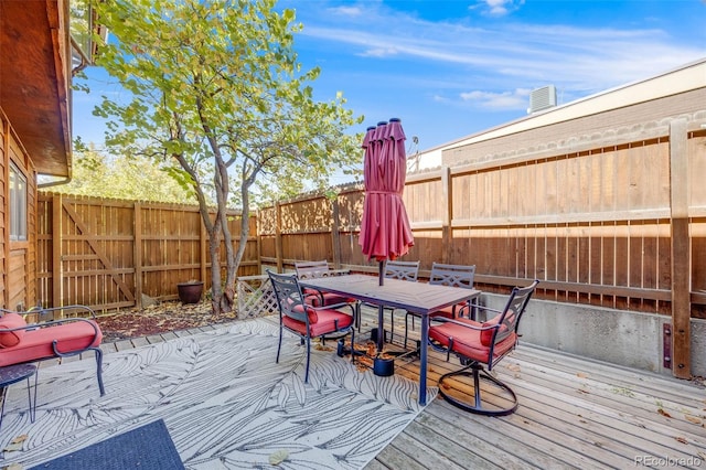 wooden deck with outdoor dining space and a fenced backyard