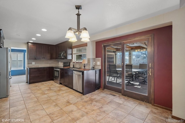 kitchen featuring pendant lighting, a notable chandelier, decorative backsplash, appliances with stainless steel finishes, and dark brown cabinets