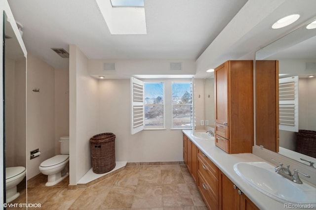 bathroom with a skylight, vanity, and toilet