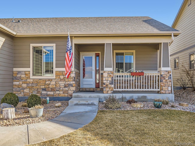 property entrance with a porch, stone siding, and roof with shingles