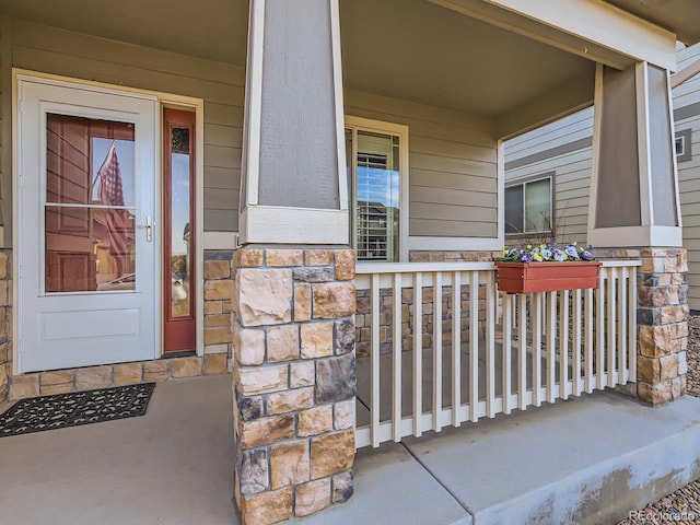 view of exterior entry featuring stone siding and a porch