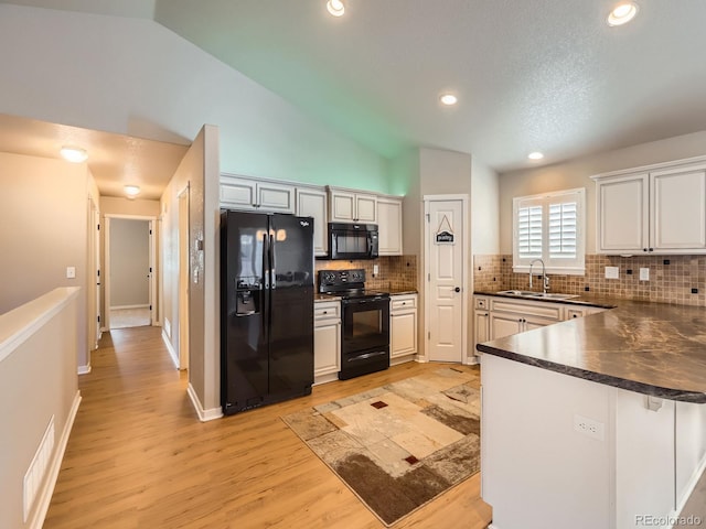 kitchen featuring dark countertops, light wood-style flooring, a peninsula, black appliances, and backsplash