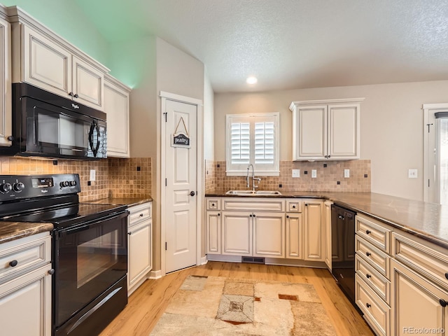 kitchen with light wood-type flooring, visible vents, a sink, and black appliances