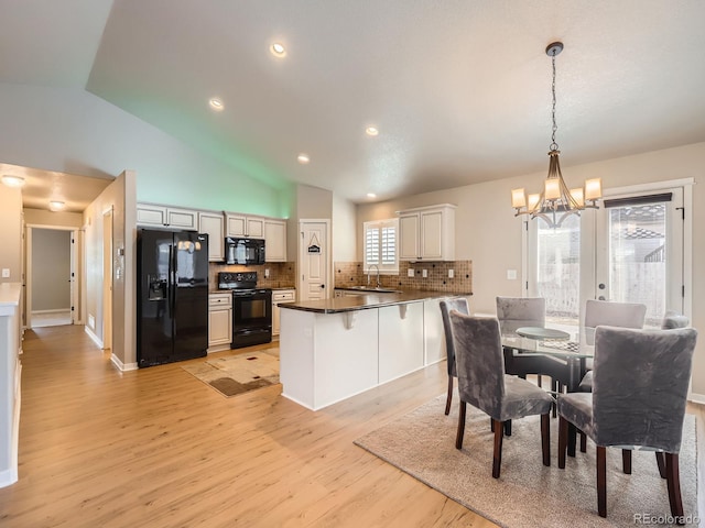 kitchen with a peninsula, black appliances, light wood-type flooring, and backsplash