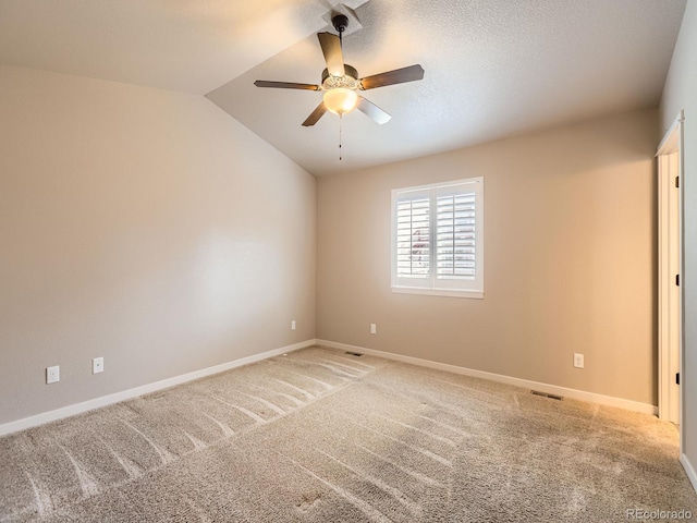 empty room featuring ceiling fan, visible vents, vaulted ceiling, and light colored carpet