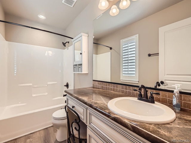 bathroom featuring visible vents, shower / bathing tub combination, toilet, vanity, and wood finished floors