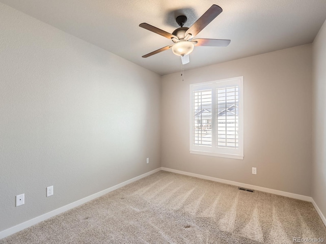 unfurnished room featuring carpet floors, a ceiling fan, visible vents, and baseboards