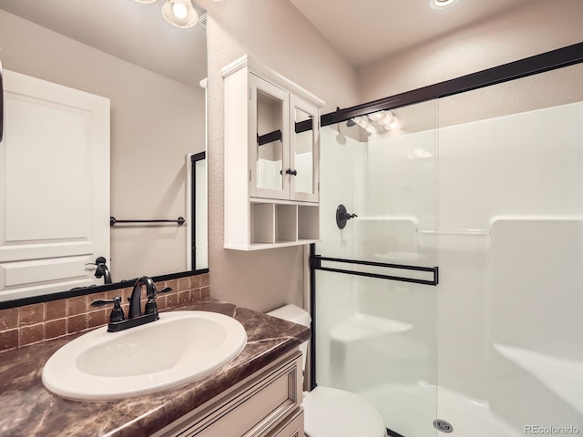 bathroom featuring a shower stall, toilet, and vanity