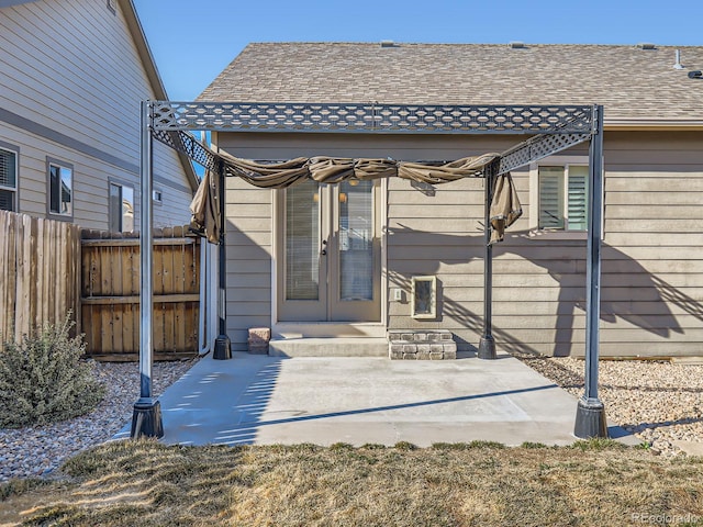 rear view of property with roof with shingles, fence, and a patio