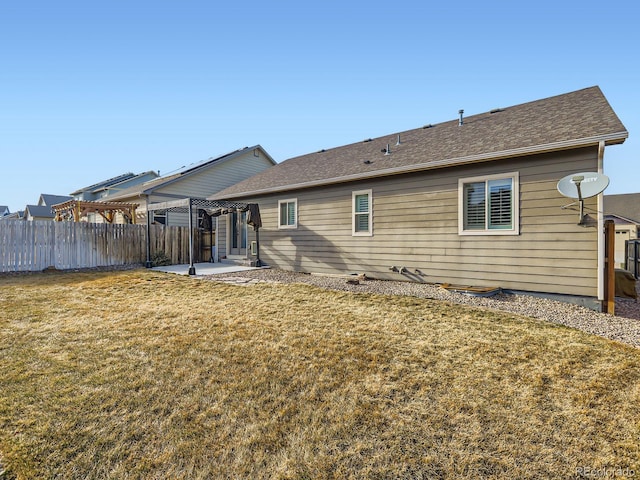 back of property with roof with shingles, fence, a yard, a patio area, and a pergola