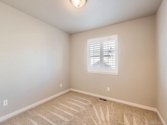 spare room featuring baseboards, visible vents, and carpet flooring