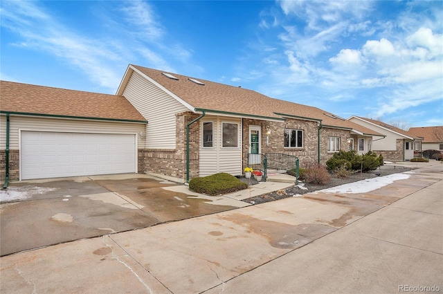 view of front of home with a garage, a shingled roof, concrete driveway, and brick siding