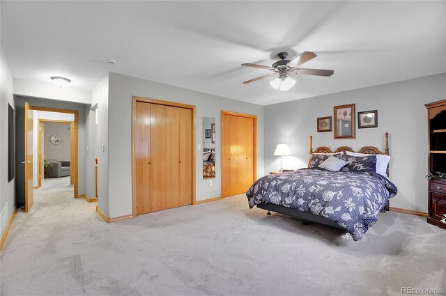 bedroom with baseboards, a ceiling fan, light colored carpet, and multiple closets