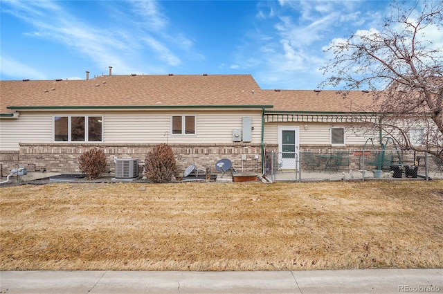 back of property featuring a yard, central AC, and brick siding