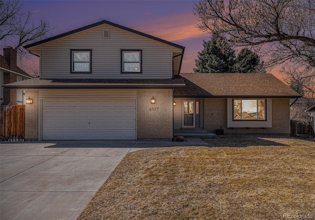 traditional home featuring fence, a lawn, brick siding, and driveway