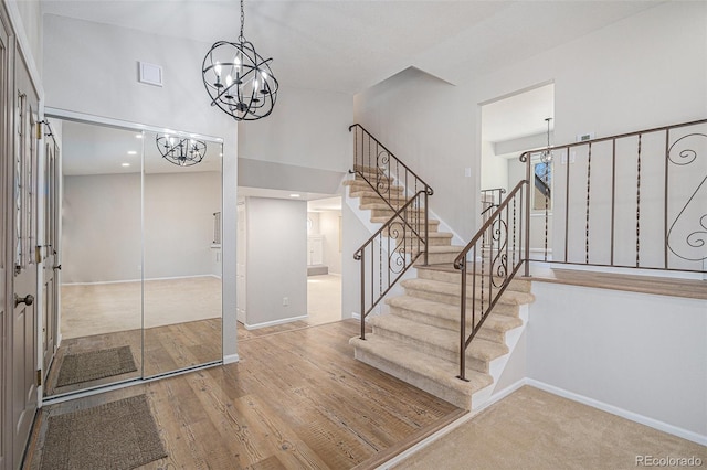 stairs featuring baseboards, a notable chandelier, a high ceiling, and wood finished floors