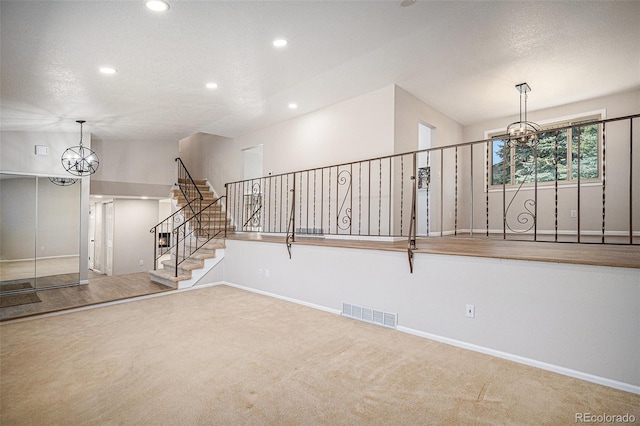 unfurnished living room featuring visible vents, carpet, an inviting chandelier, and stairway